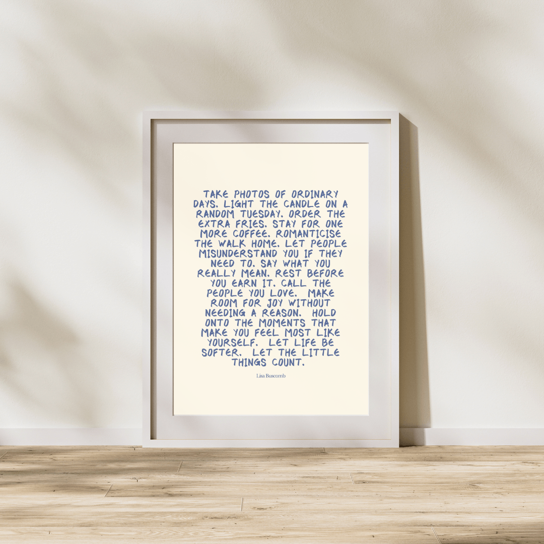 Framed print with a motivational quote on a wooden surface and light-colored wall background