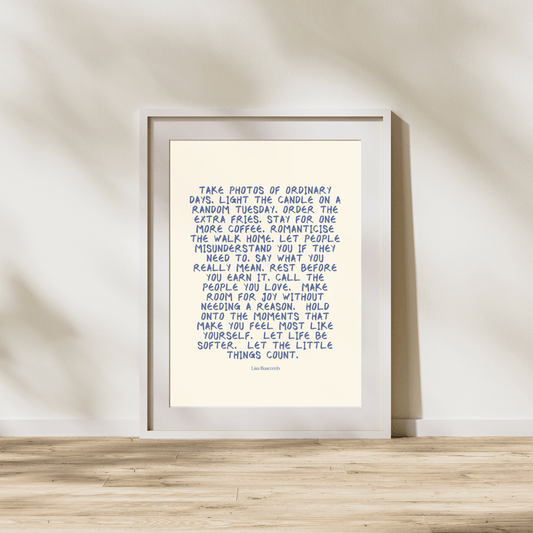 Framed print with a motivational quote on a wooden surface and light-colored wall background
