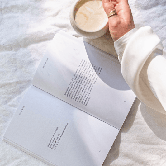 Open pages of the WILD SELF-LOVE Book by Lisa Buscomb with a cup of coffee, showcasing inspirational self-love reminders.