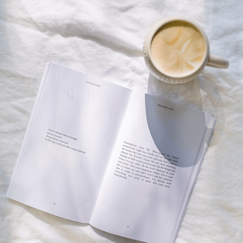 Open page of WILD SELF-LOVE Inspirational Self-Love Book by Lisa Buscomb with a cup of coffee.