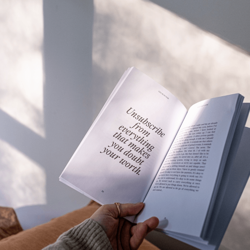 Inspirational Self-Love Book by Lisa Buscomb open to a page with the quote "Unsubscribe from everything that makes you doubt your worth."